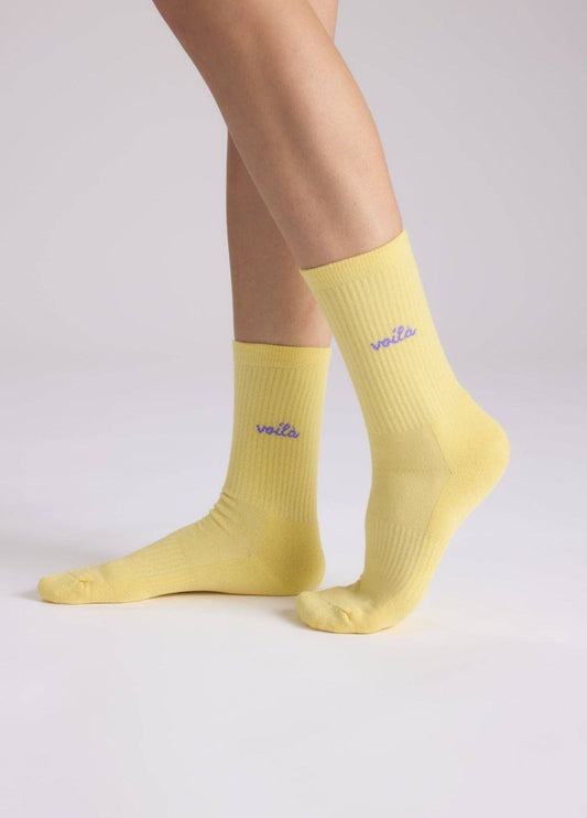 VOILÀ Statement Socken von NBDC in Gelb mit violettem Schriftzug getragen – Nohna