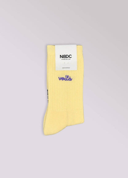 VOILÀ Statement Socken von NBDC in Gelb mit violettem Schriftzug Produktverpackung – Nohna