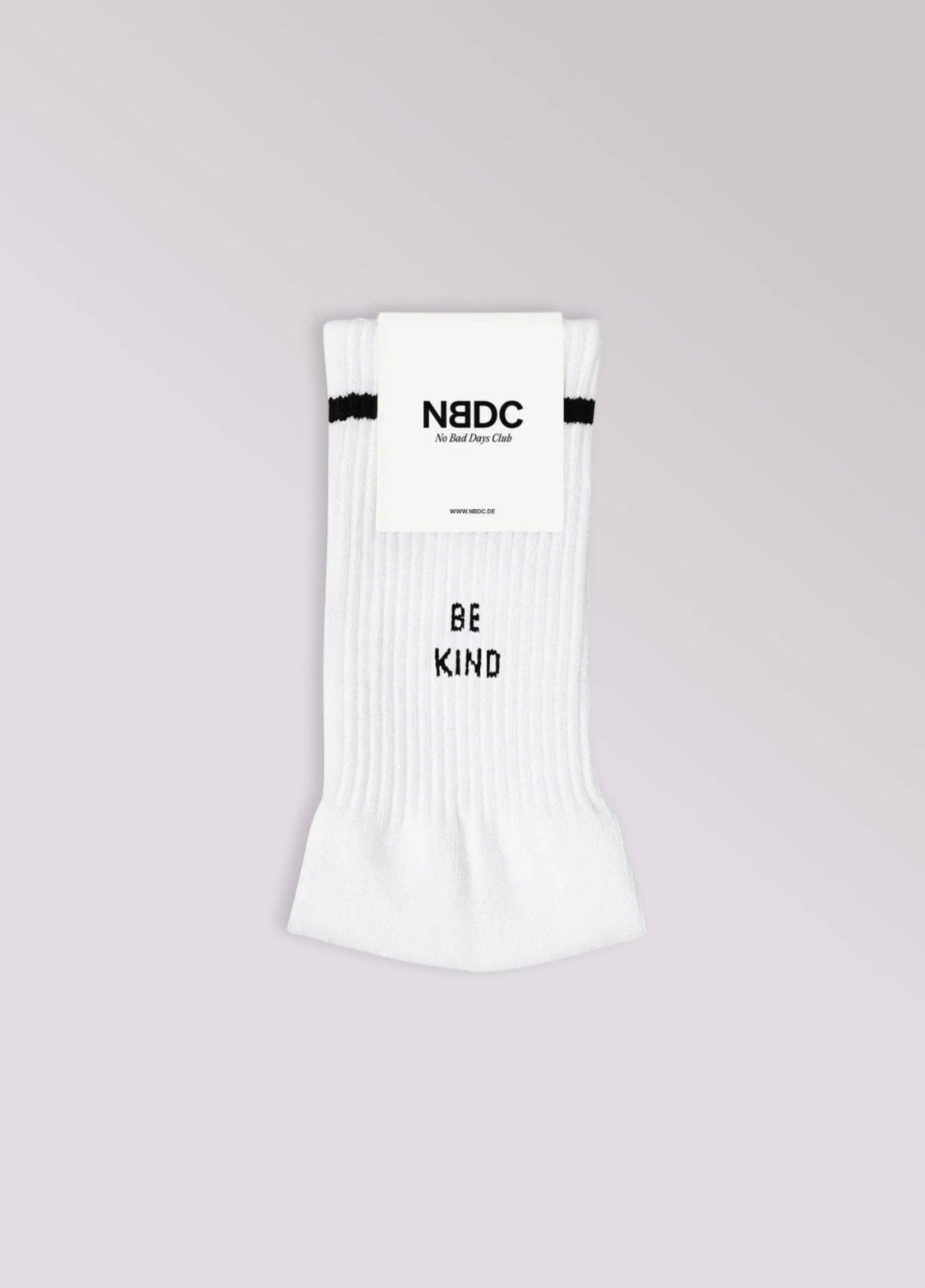 BE KIND Statement Socken von NBDC in Weiß mit schwarzem Schriftzug Produkverpackung – Nohna