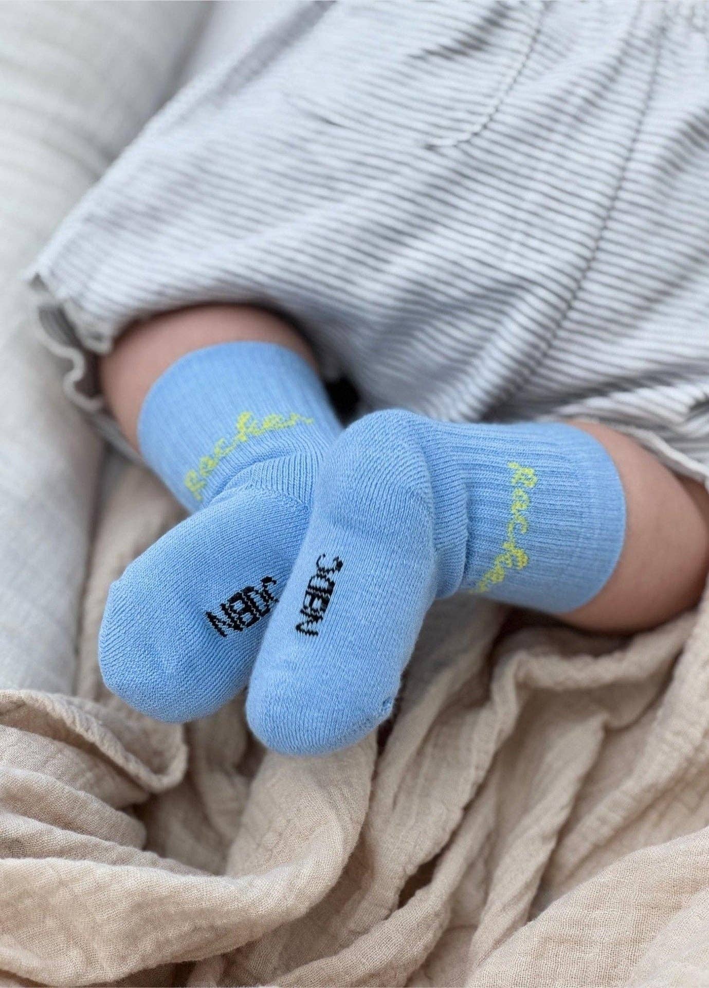 RACKER Socken in Hellblau mit grünem Schriftzug für Babys und Kinder von NBDC getragen – Nohna
