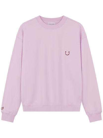 Croissant Sweatshirt Unisex in hellem Rosa mit Smiley-Print und Croissant-Stickerei am Ärmel – Frontansicht - Nohna