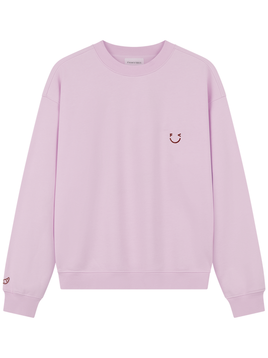 Croissant Sweatshirt Unisex in hellem Rosa mit Smiley-Print und Croissant-Stickerei am Ärmel – Frontansicht - Nohna