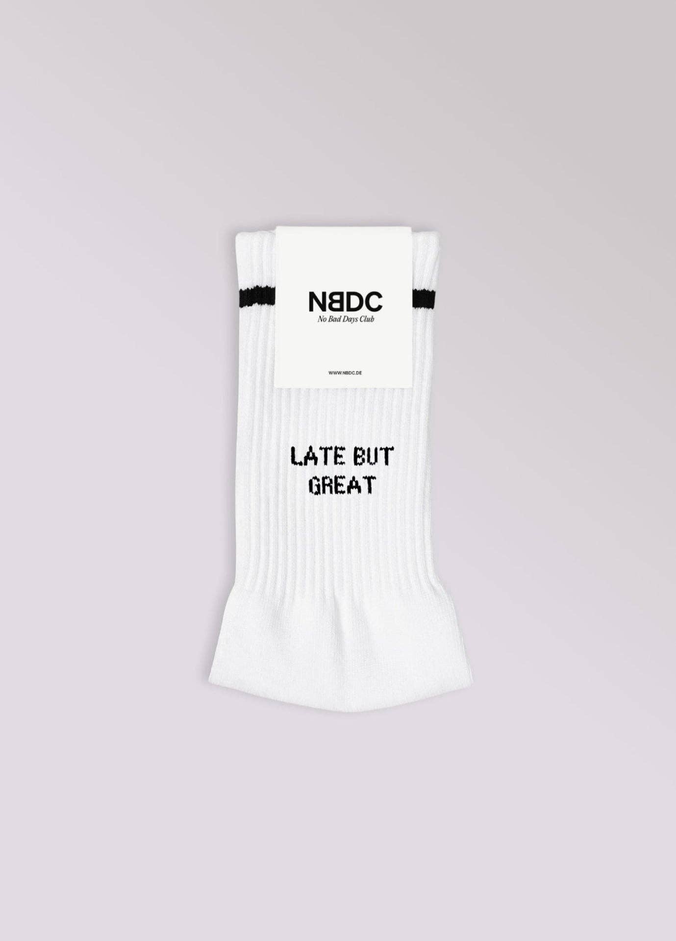 LATE BUT GREAT Statement Socken von NBDC in Weiß mit schwarzem Schriftzug Produktverpackung – Nohna